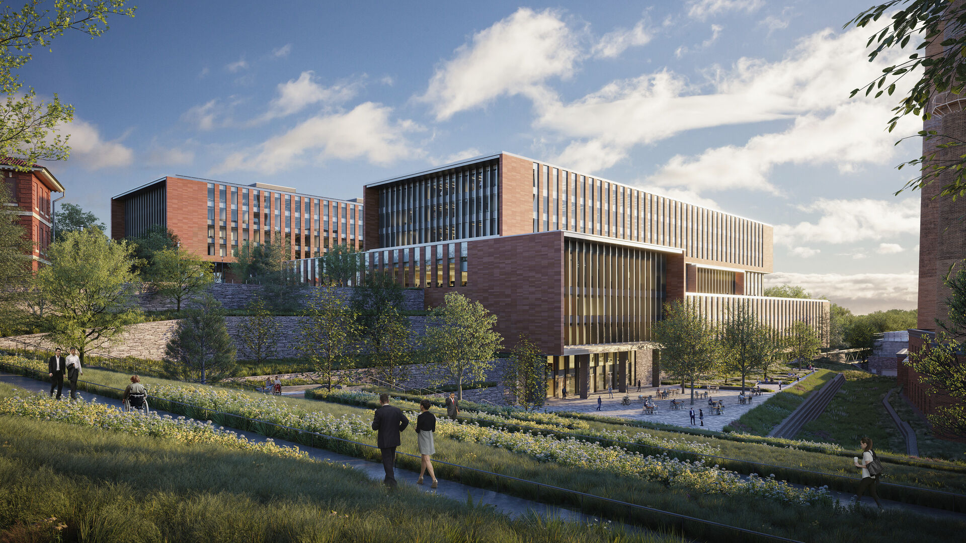 A rendering of the new CISA HQ building and central utility plant. The buildings are red brick and surrounded by green landscaping. There is a large, terraced office building in the center with two main towers. Two tall smokestacks from the utility plant are just visible on the right side.